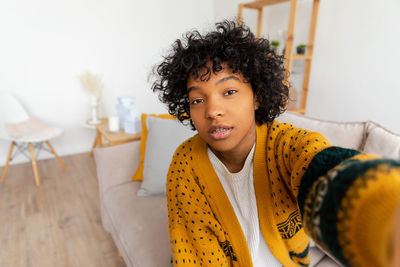 Portrait of young woman standing against wall