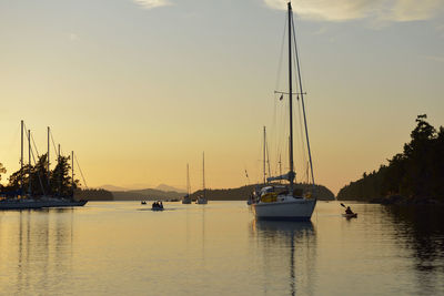 Sailboats moored in marina at sunset