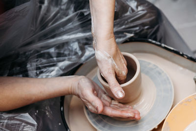 Close up of woman hands molding clay mug spinning on pottery wheel. potter hands forming clay cup