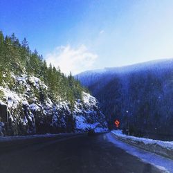 Road leading towards mountains against blue sky