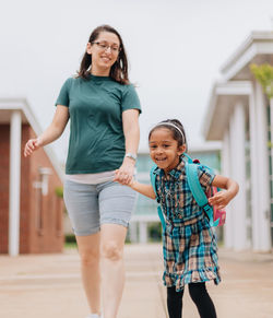 Young millennial mother sending daughter off back to school