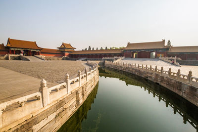 View of river by buildings against clear sky