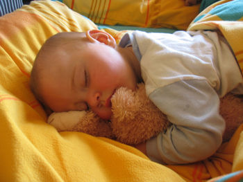 Cute baby sleeping on bed with teddy