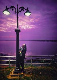 Full length of woman standing by sea against sky during sunset