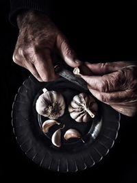 Directly above of man peeling garlic against black background