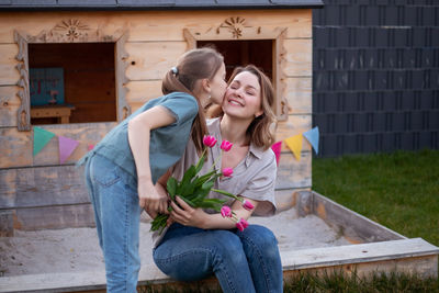 Daughter kissing mother in backyard on birthday