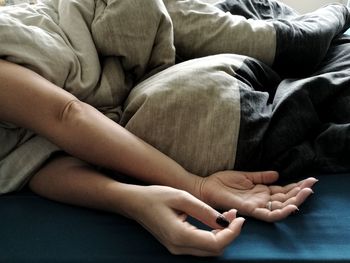 Low section of child relaxing on bed at home