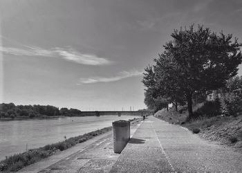 Footpath by lake against sky