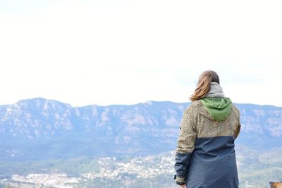 Rear view of woman standing on mountain against sky