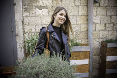 Portrait of smiling young woman standing against brick wall