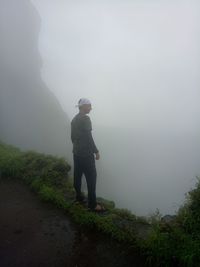 Full length of man standing on mountain during foggy weather