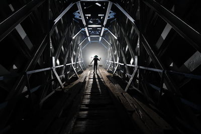 Rear view of man walking on footpath in tunnel