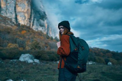 Full length of young woman standing on mountain against sky
