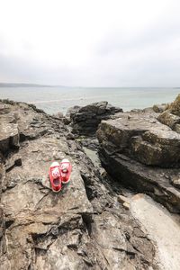 High angle view of canvas shoes of rock by sea against sky