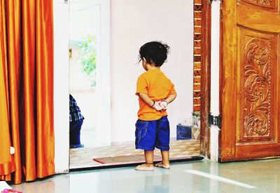 Rear view of boy standing on doorway