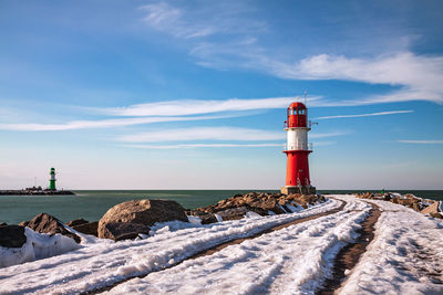 Lighthouse by sea against sky