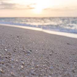 Surface level of beach against sky during sunset