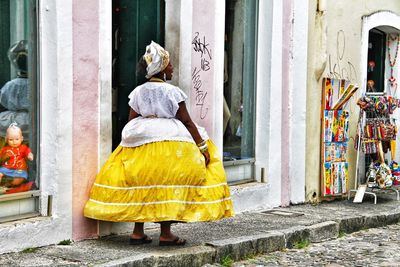 Rear view of woman standing against yellow building