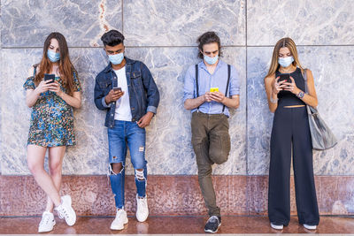 Group of people using mobile phone against wall