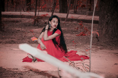 Full length portrait of woman sitting on land