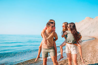 Friends standing on beach against sky