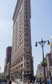 Low angle view of people in city against clear sky