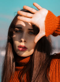 Close-up portrait of young woman shielding eyes