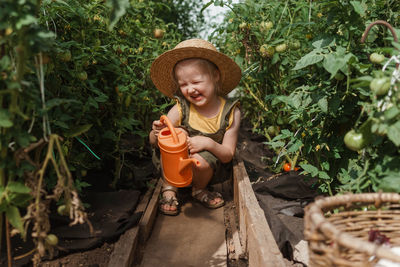 Full length of girl watering plants at farm