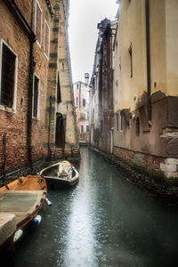 Canal amidst city against sky