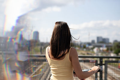 Rear view of woman standing in city against sky