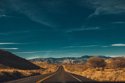 Empty road along landscape against sky