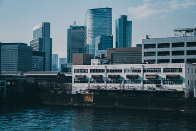 Modern buildings by river against sky in city