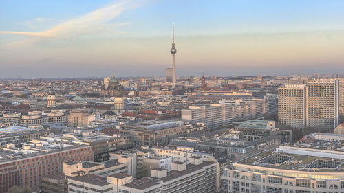 Fernsehturm amidst cityscape against sky during sunset