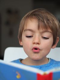 Close-up of boy reading book at home