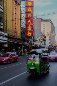 Traffic on road by buildings in city