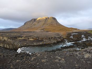 Scenic view of land and mountains against sky