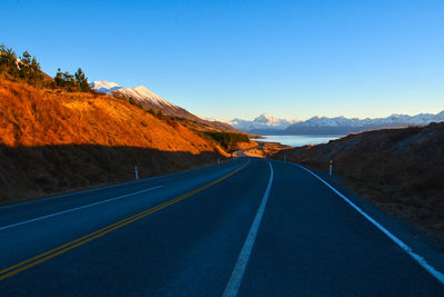 Road amidst mountains against clear blue sky