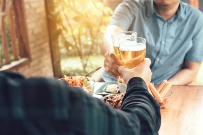 Midsection of man drinking glass on table