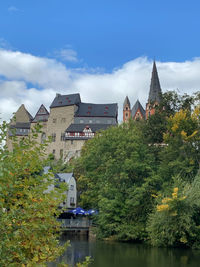 Buildings by river against sky