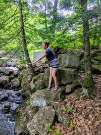 Full length of woman standing on rock in forest