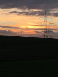 Silhouette of power lines against cloudy sky