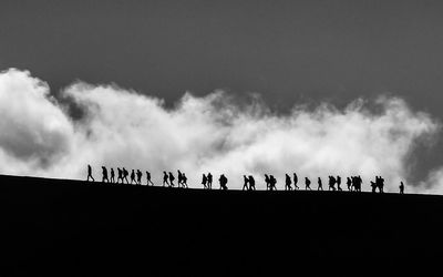 Silhouette people on land against sky