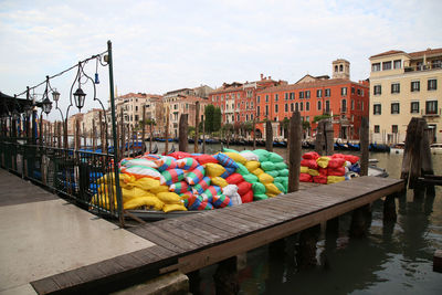 Multi colored boats in canal amidst buildings in city against sky