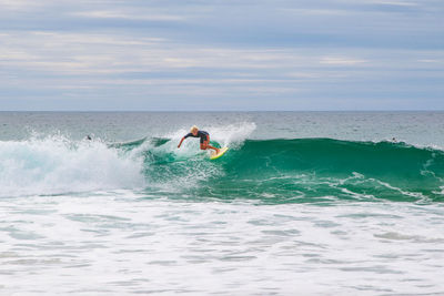 Man surfing in sea against sky