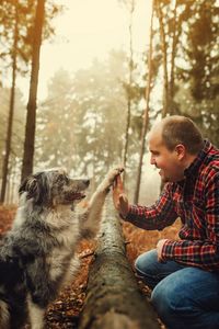 Side view of man with dog in forest during foggy weather