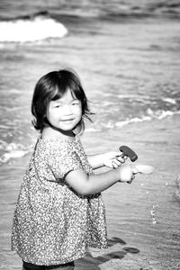 Portrait of girl holding toys at beach