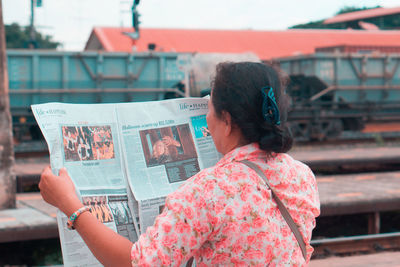 Rear view of woman holding umbrella in city