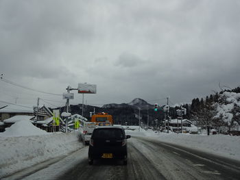 Cars on road in winter against sky