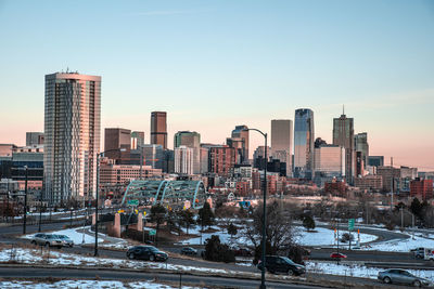 Modern buildings in city against sky during sunset