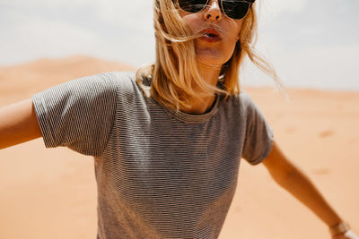 Portrait of woman in sunglasses standing on desert in sunny day